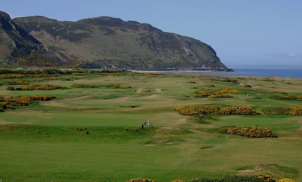 Conwy Golf Club’s coastal links, with fairways and gorse beneath a rocky headland.